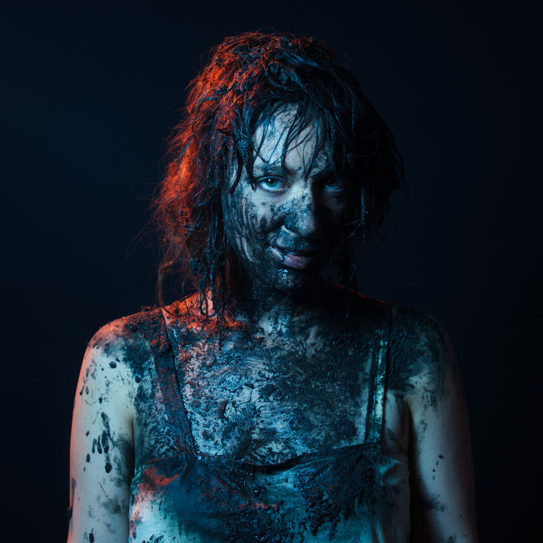 Portrait close-up of actor Emily Goddard covered in mud as promotional image for her theatre piece 'This is Eden'