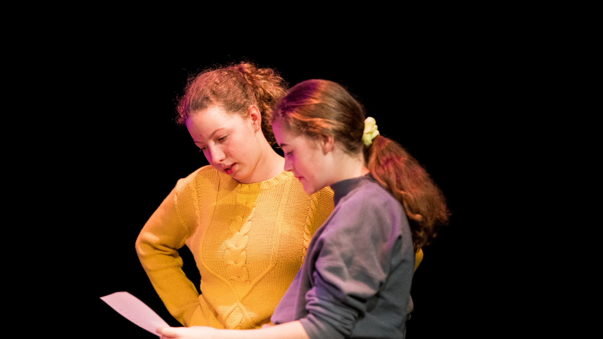Two youth arts performers reviewing a script together. 