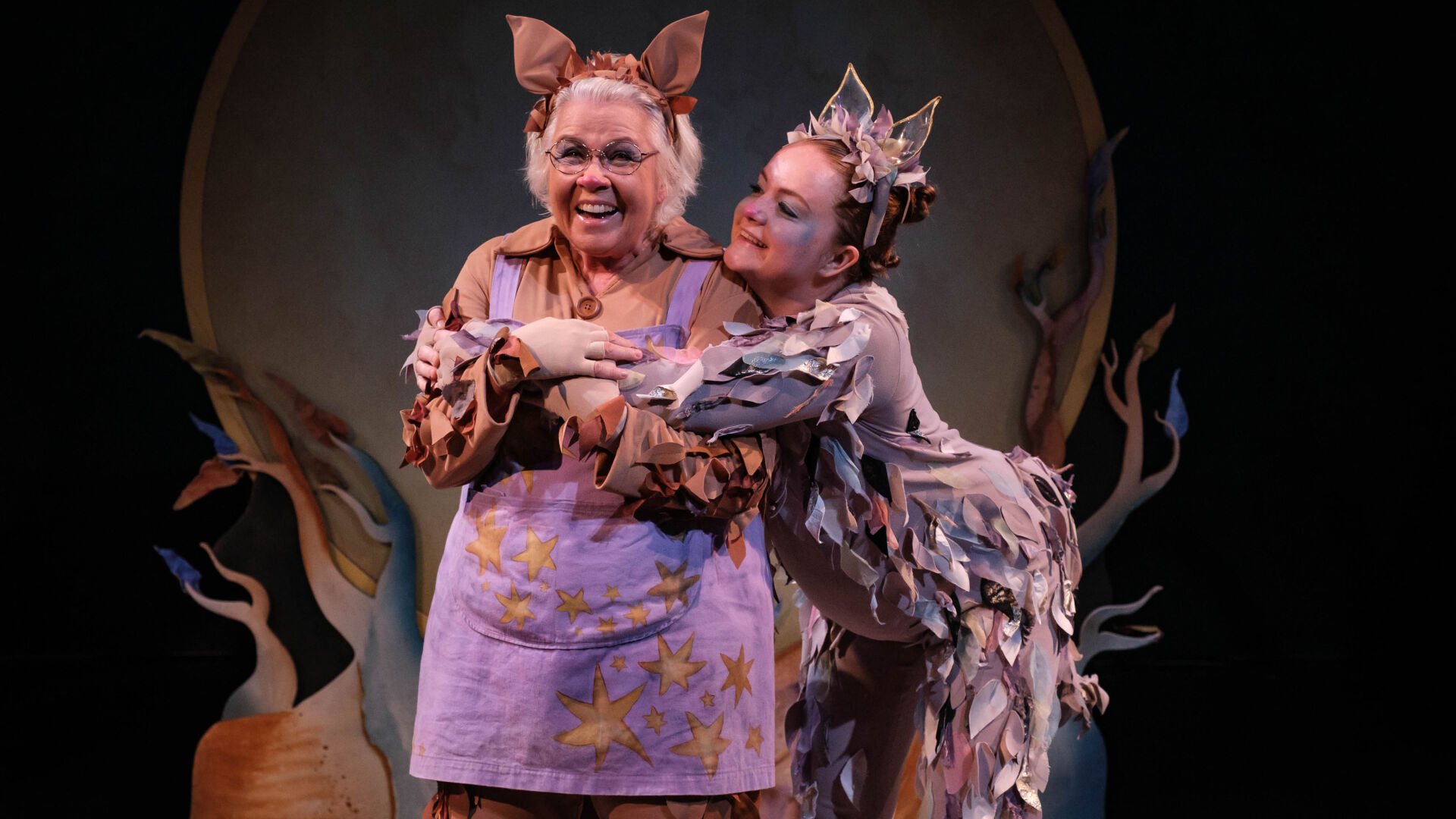 Actors in costume as Grandma Poss and baby possum hug