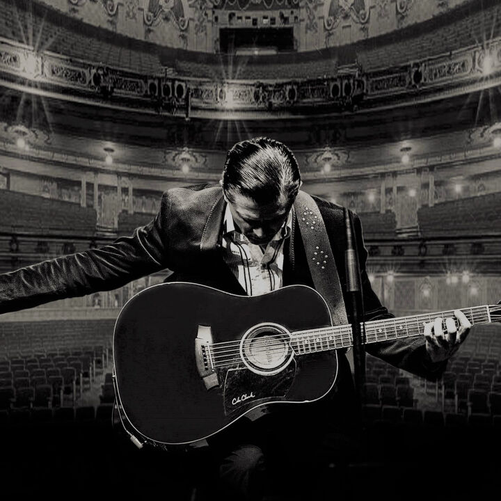A man taking a bow on the stage with his guitar